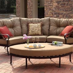 a couch and coffee table on a brick patio with flowers in vases sitting on it