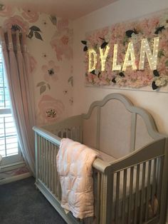 a baby's room decorated in pink and gray with flowers on the wall, crib