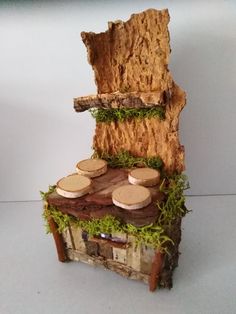 a small wooden structure with cheeses on top and moss growing out of the wood