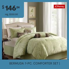 a bed with green comforter and pillows on it