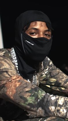 a woman wearing a black mask and camouflage jacket