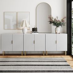 a white and black striped rug in front of a sideboard with two vases on it