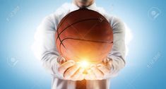 a man holding a basketball in his hands with the sun shining through it stock photo