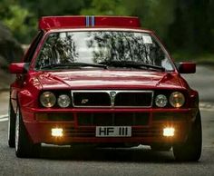 a red car driving down the road with its lights on and headlamps on