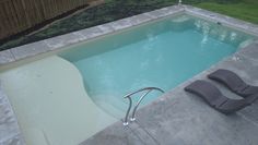 an empty swimming pool with lounge chairs next to it