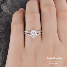 a woman's hand with a diamond ring on top of her finger and the other hand holding it