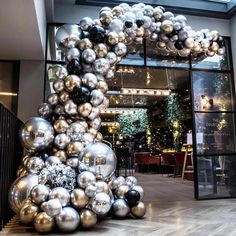 a bunch of silver and black balloons in front of a building