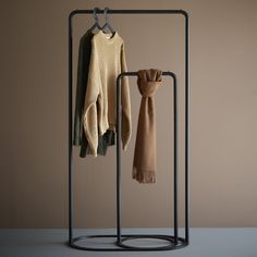 two sweaters and a scarf hanging on a clothes rack