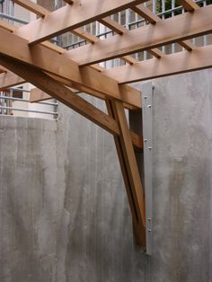 an unfinished wooden structure in front of a concrete wall with metal bars on the sides