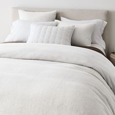 an unmade bed with white linens and pillows