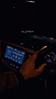 a person is driving in the dark with their hands on the steering wheel and dashboard