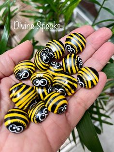 yellow and black striped beads in the palm of someone's hand with green leaves