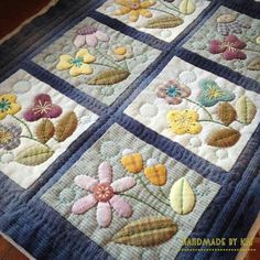 a quilted table runner with flowers and leaves on the edges, in blue tones