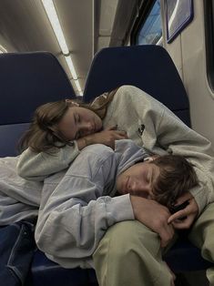 two people sleeping on a train next to each other with their arms around each other