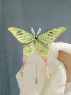 a green butterfly sitting on top of a white towel