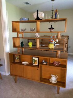 a wooden shelf with pictures and vases on it in the corner of a room