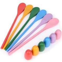colorful plastic spoons lined up next to each other on a white surface with balls