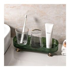 a green tray with two toothbrushes and three cups on it