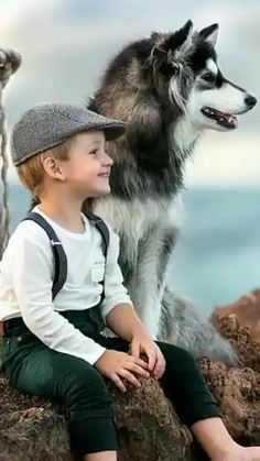 a little boy sitting on top of a rock next to a dog