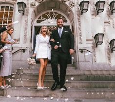 a man and woman are walking down the steps with confetti in front of them