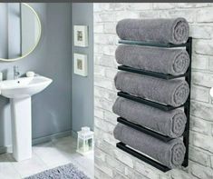 towels are hanging on the wall next to a bathroom sink and towel rack in front of a white brick wall