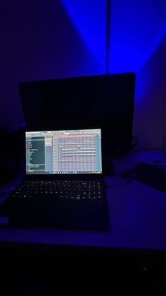 a laptop computer sitting on top of a desk in front of a dark blue background