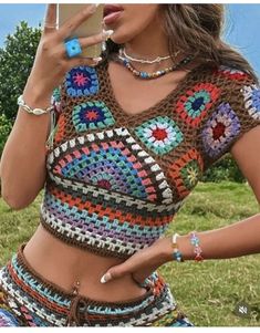 a woman in a crochet top holding a cell phone