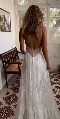 the back of a woman's dress in front of a window with a bench