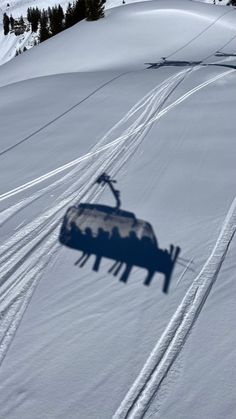 the shadow of a ski lift is cast on snow
