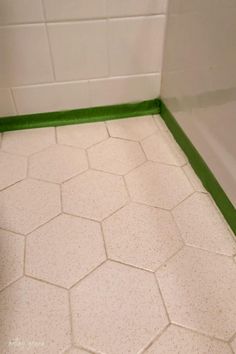 a bathroom with white tile and green trim