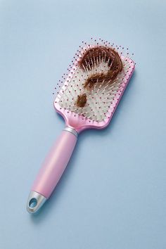 a pink hair brush sitting on top of a blue surface