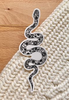 the snake sticker is on top of a white knitted blanket with wood flooring