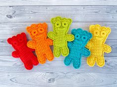 four crocheted teddy bears sitting next to each other on a white wooden surface