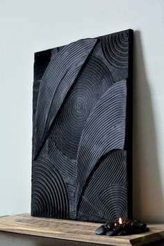 a black sculpture sitting on top of a wooden shelf next to a candle and some rocks