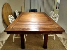 a wooden table with white chairs around it in the middle of a carpeted room