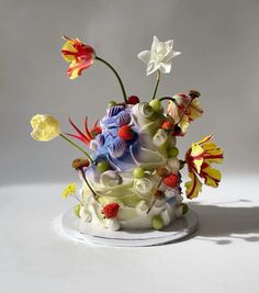 a white cake with flowers and fruit on it