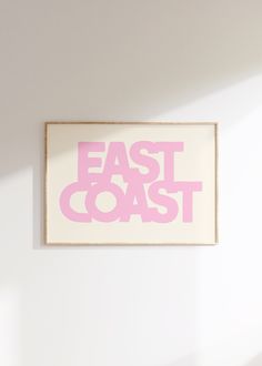 a pink and white sign that says east coast on it's wall above a bed