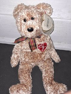 a brown teddy bear with a red heart on it's chest sitting next to a white wall