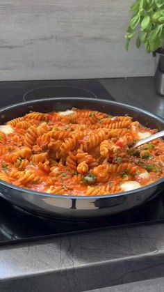 a pan filled with pasta and sauce on top of a stove