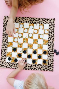 two children playing checkers on a leopard print mat with black and white squares in the middle