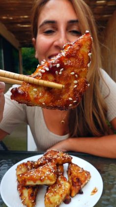 a woman is eating food with chopsticks over her face
