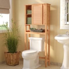 a bathroom with a toilet, sink and wooden cabinet in it's center area