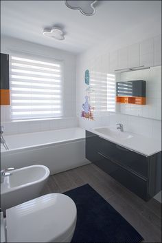 a bathroom with two sinks and a bathtub next to a window covered in blinds