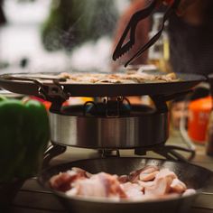 a person cooking food on top of a stove with tongs and an open skillet