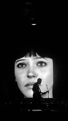 black and white photograph of a woman's face in front of a television screen