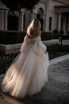 a woman in a white dress is walking down the street