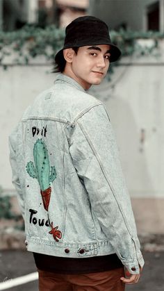 a young man wearing a jean jacket with a cactus design on the front and back