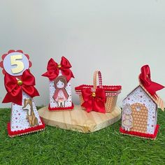 three little houses made out of paper with red bows and decorations on the top, sitting in grass