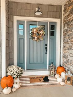 a blue front door with pumpkins and flowers