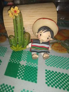 a small figurine sitting next to a cactus